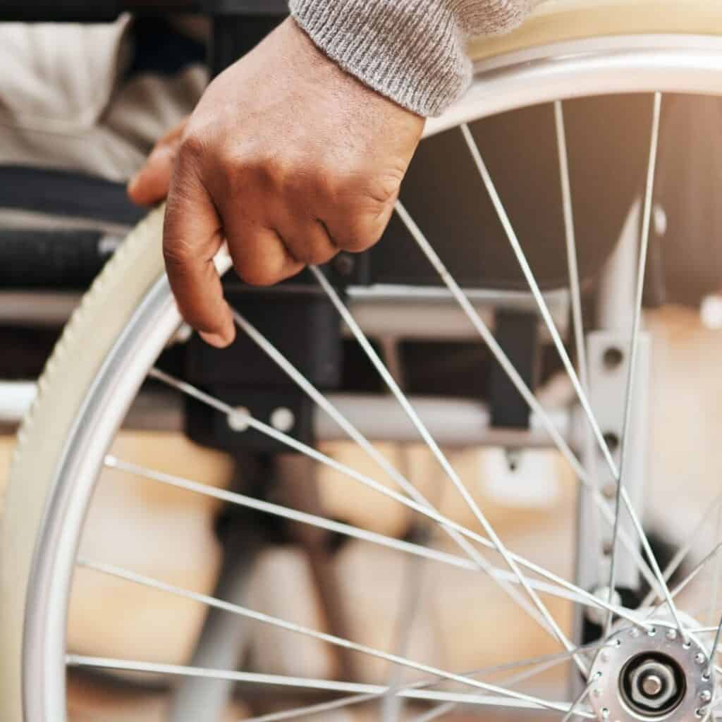 be handicap friendly or accessible at yard sale.  image; wheel of wheelchair with hand
