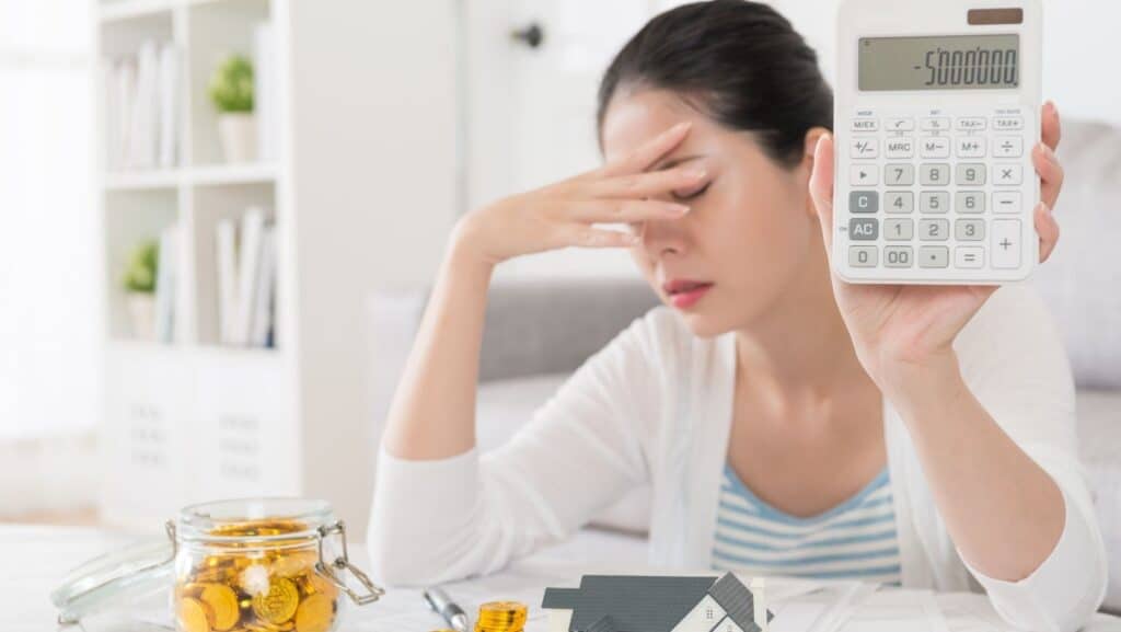 tips for startomg or re-vising your Budget image is woman holding calculator looking stressed
