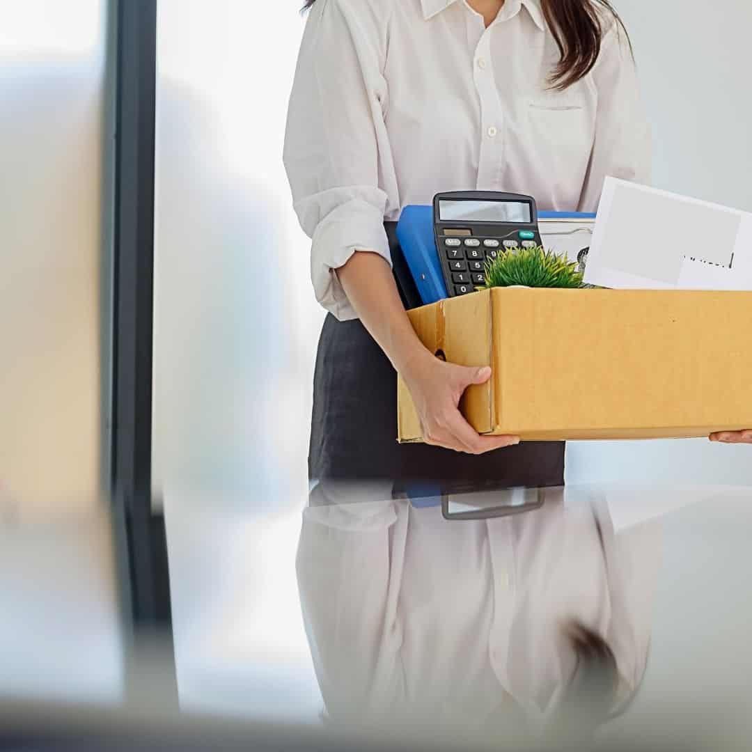 What To Do If You Get Laid Off & How To Survive Financially. Image of woman carrying out office items in a box