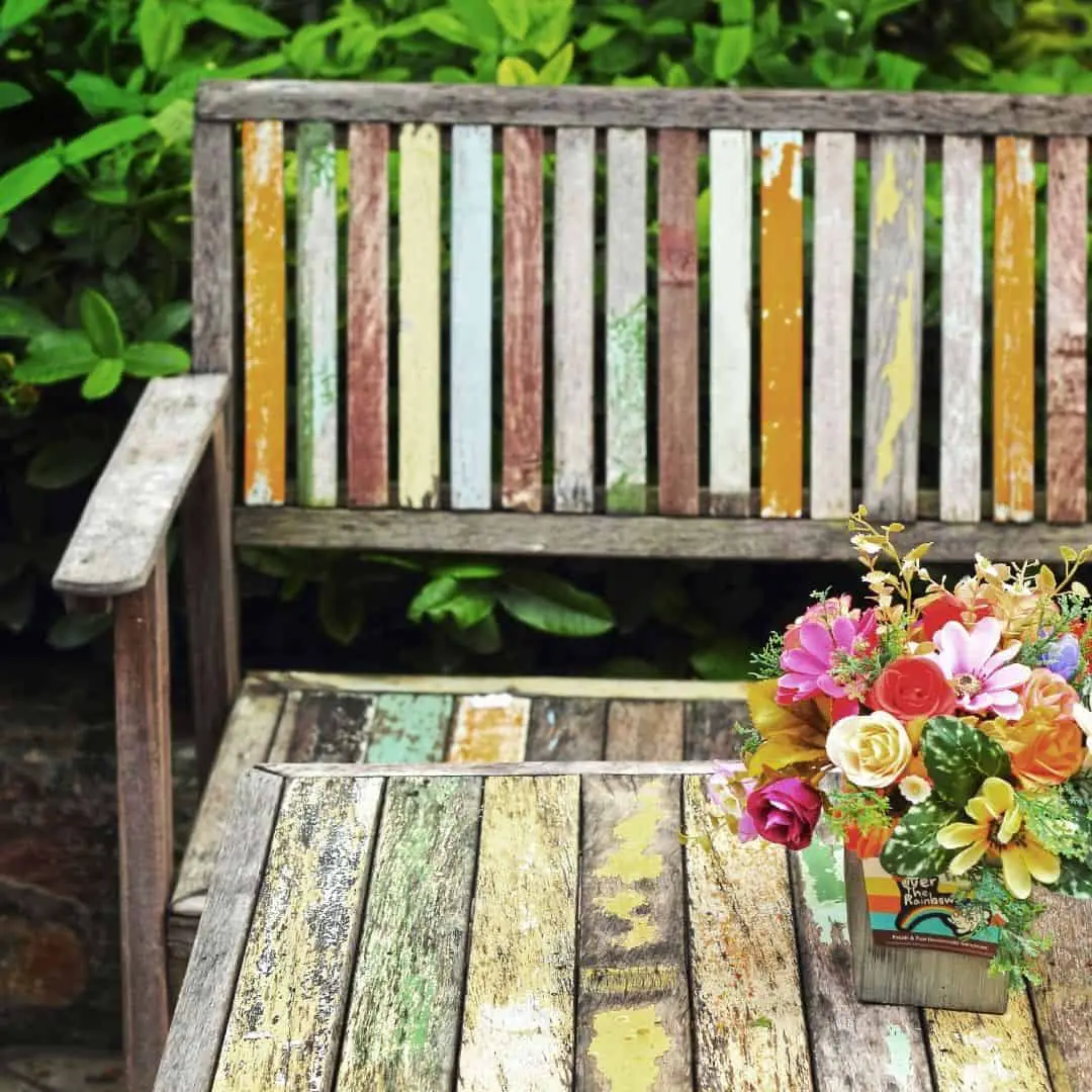 tips for living on a fixed income. image of outdoor painted bench with vase of flowers placed in center of seat, depicts simple living