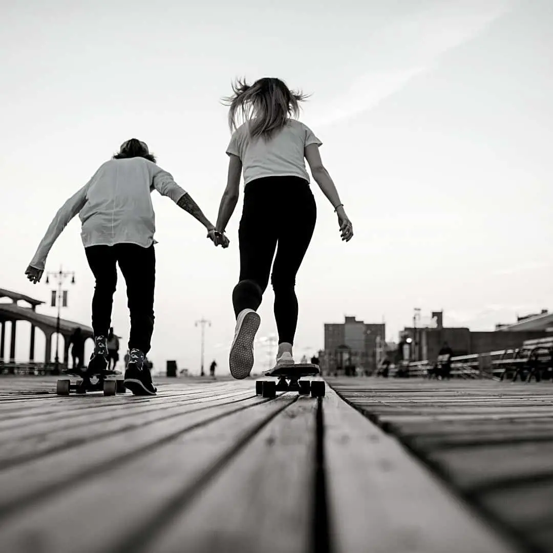 Long & Short Term Financial Goals For High School Students Article. Image of two teenagers skateboarding away on boardwalk (black and white image)